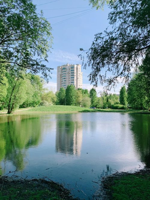A serene view of a park in St. Petersburg featuring a clear reflection of a building on a pond.